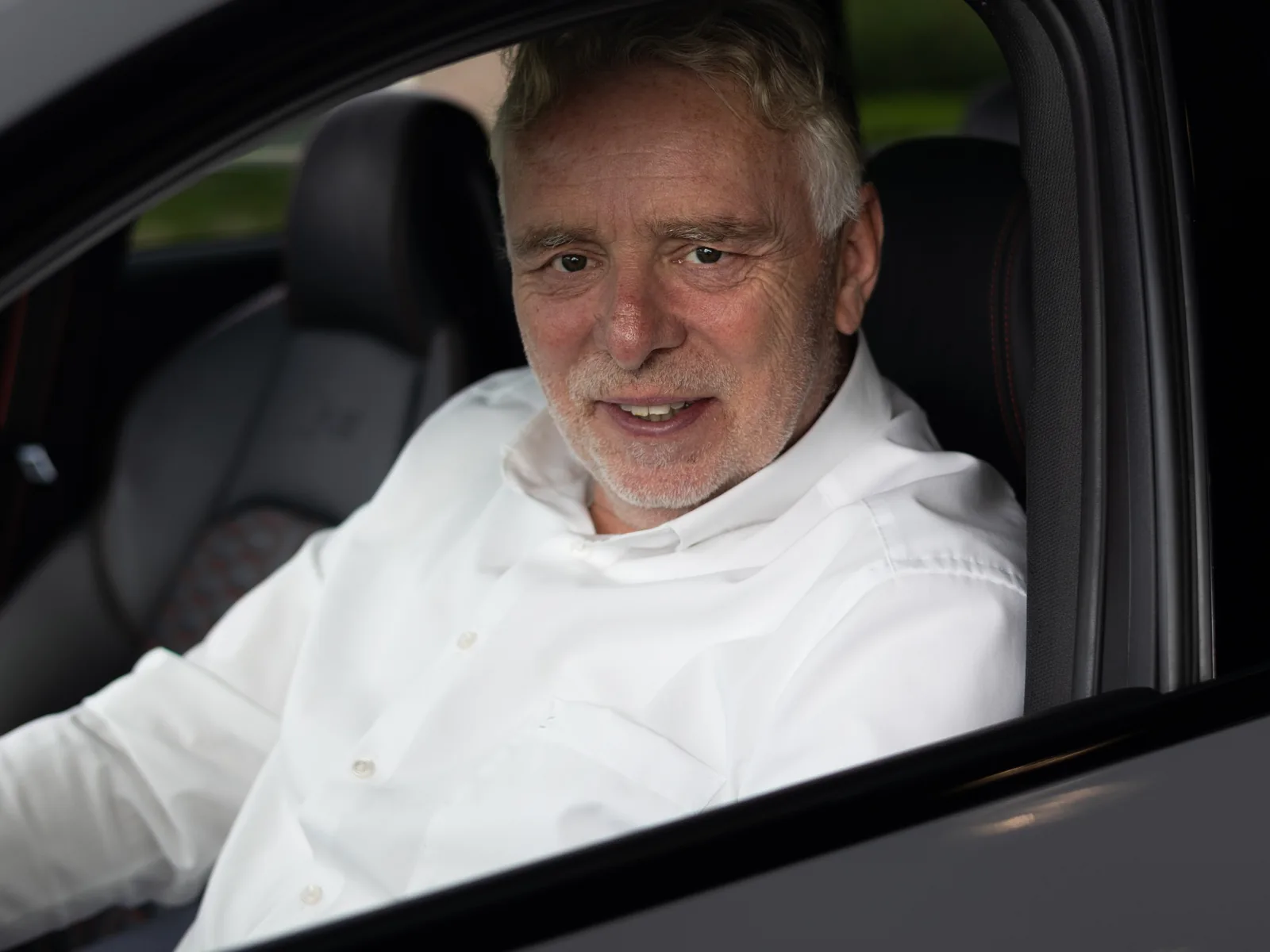 Frank Kamminga van AIG Automotive achter het stuur van een auto in de showroom